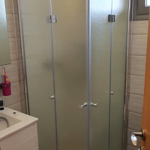 מקלחון זכוכית עם דלתות מתכת בחדר אמבטיה