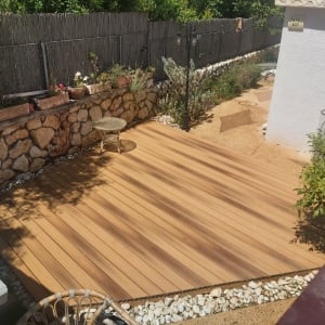 דק עץ בגינה עם עציצים ואבנים מסביב