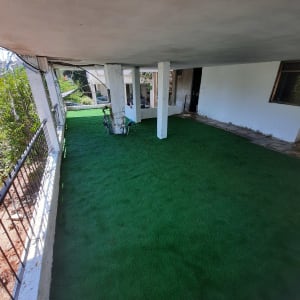 דשא סינתטי ירוק על מרפסת עם מעקה ברזל