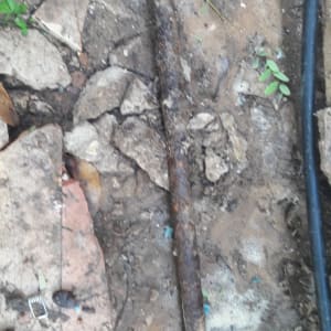 צינור חלוד באדמה עם אבנים מסביב