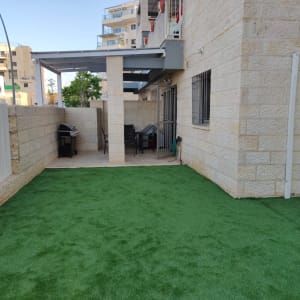 דשא סינתטי בחצר עם גריל ופינת ישיבה