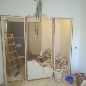 חדר בשיפוץ עם קיר שבור, סולם ופסולת בנייה