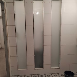 שלושה לוחות זכוכית חלבית מותקנים בקיר אריחים