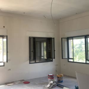 חדר בשיפוץ עם דלי צבע, כבלים וכלים על הרצפה