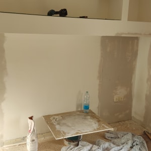 קיר עם תיקוני גבס, כלי עבודה וחומרי בנייה