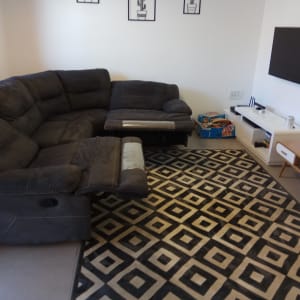 ספה פינתית כהה על שטיח גיאומטרי שחור לבן