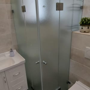 מקלחון זכוכית עם דלתות מתכת בחדר אמבטיה