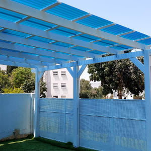 פרגולה מעץ עם גג פלסטיק כחול בגינה