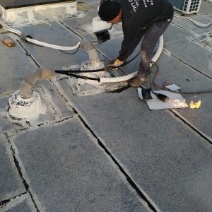 אדם מבצע איטום גג עם מבער להבה