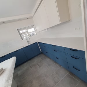 מטבח נקי עם ארונות כחולים ומשטח עבודה לבן