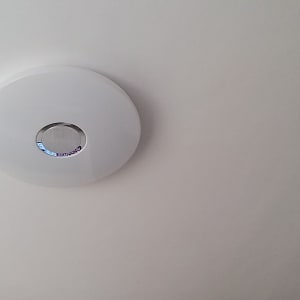 גלאי עשן עגול מותקן על תקרה לבנה