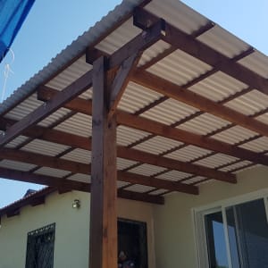 פרגולה מעץ עם גג מתכת בחצר הבית