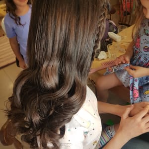 שיער גלי עם צמה בצד, מסרק ורוד ביד