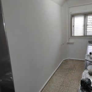 קיר צבוע בלבן עם כלים לצביעה על שולחן