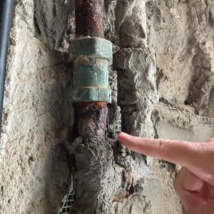 צינור חלוד עם חיבור מתכת בקיר בטון