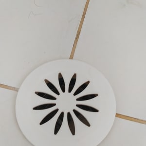 פתח ניקוז עגול ברצפה עם מכסה לבן