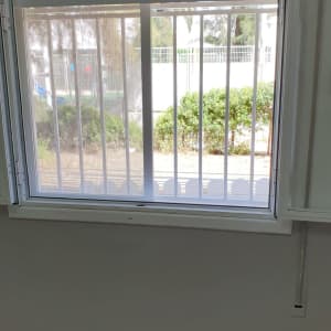 חלון עם מסגרת לבנה וסורגים אנכיים