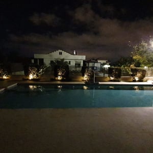 בריכת שחייה מוארת בלילה עם תאורת גן