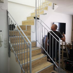 מעקה מתכת בצבע אפור על מדרגות עץ