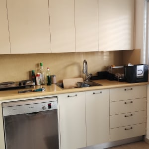 מטבח עם כיור, מדיח כלים ובקבוקים על השיש