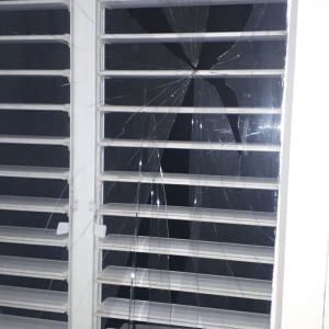 זכוכית שבורה בחלון עם תריסים לבנים