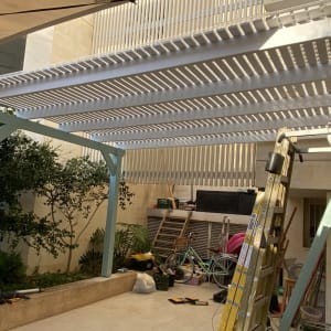 פרגולה לבנה עם עמודי תמיכה בגינה