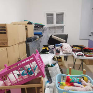 חדר עם קופסאות קרטון, בגדים מקופלים וסל צעצועים