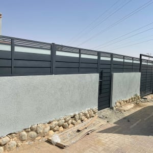 שער חשמלי מתכת כהה על גדר בטון