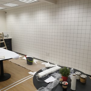 קיר עם טפט מרובע, שולחנות עם כלים וחומרים