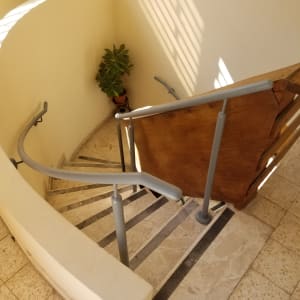 מעקה מתכת אפור על גרם מדרגות מעץ ואבן