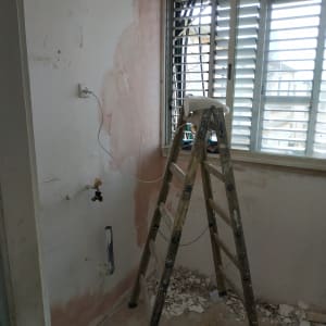 סולם ליד קיר עם טיח מתקלף וחלון