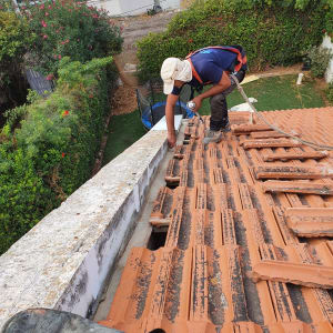 עובד על גג רעפים עם כלי עבודה ביד