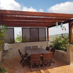 פרגולה מעץ עם שולחן וכיסאות בגינה