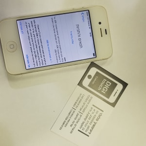 אייפון לבן עם מסך טקסט בעברית על שולחן