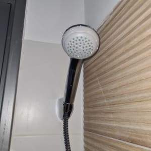 ראש מקלחת עם צינור גמיש על קיר אריחים