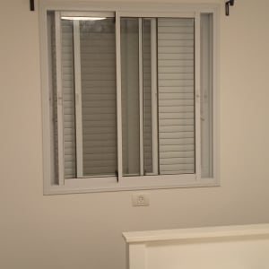 חלון עם תריסים סגורים על קיר לבן