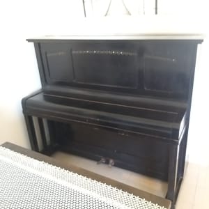 פסנתר עומד כהה עם גלגלים קטנים בתחתית