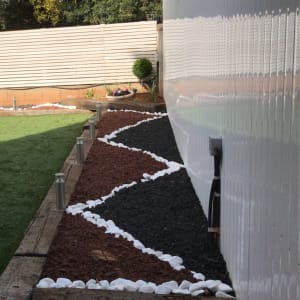 אבנים לבנות ושחורות בגינה עם שביל עץ