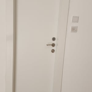 דלת לבנה עם ידית מתכת על רקע קיר לבן