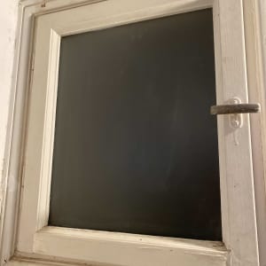 חלון עם זכוכית כהה במסגרת עץ לבנה