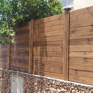 גדר עץ חומה עם עמודים, על קיר אבנים