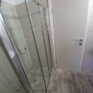 מקלחון זכוכית עם דלתות הזזה ורצפת אריחים