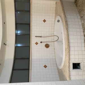 אמבטיה עם אריחים לבנים וברז נחושת