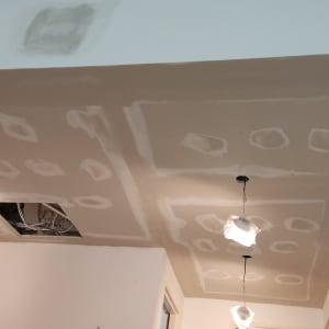 תקרת גבס עם תיקונים וחוטי חשמל חשופים