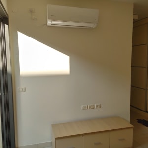 קיר לבן עם מזגן תלוי וצל על הקיר