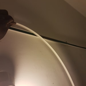 יד מחזיקה כבל חשמל ליד מנורה על קיר