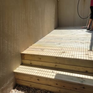 מדרגות עץ עם חצץ מסביב ואדם עם צינור מים