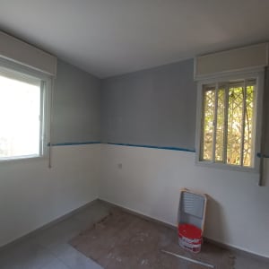 חדר צבוע חלקית עם דלי צבע ומגש צביעה