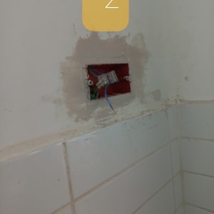 חוטי חשמל חשופים בקופסת חיבורים בקיר