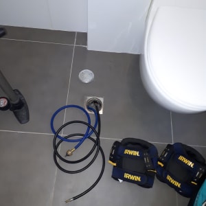 צינור כחול ושחור מחובר לרצפה ליד אסלה